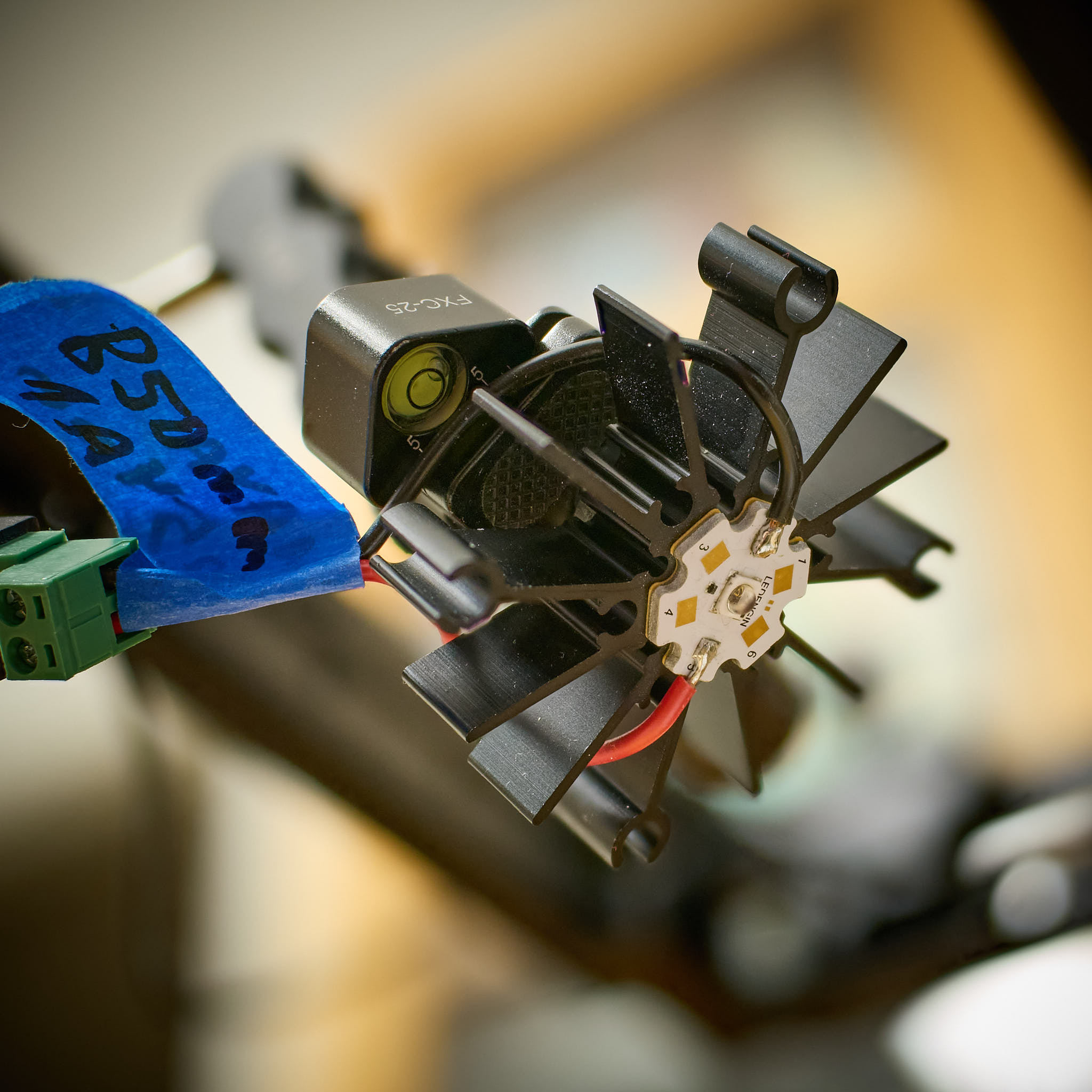 A: View of a Ledengine SMD LED. The white aluminium-core "star" PCB to which the LED is soldered, is attached with a self-stick thermal-transfer pad to a black aluminium heat sink.